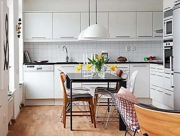 Обеденный стол, расположенный между кухней и гостиной, на самом деле многофункциональный. Он также может служить кухонным островом, учитывая, что им не хватает места для их обоих. Поскольку стол черный, он контрастирует с хрустящей белой кухней, но также обеспечивает согласованность.