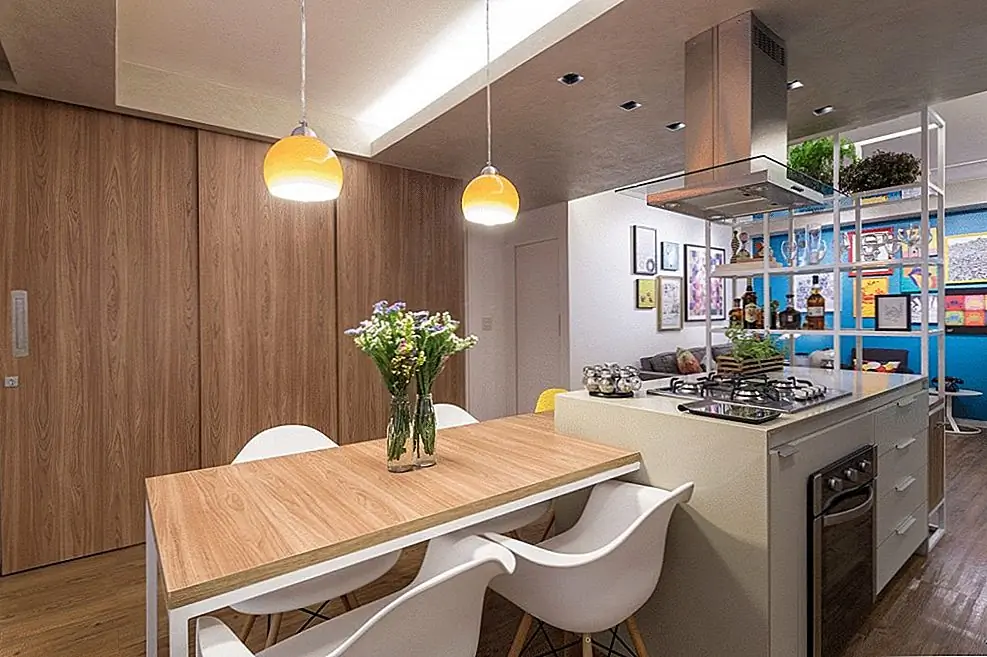 В этом районе сосредоточен остров с кухней. Это похоже на остров, а обеденный стол был растоплен вместе, и теперь они неразделимы, облегающие друг друга, как две части головоломки. Два подвешенных подвесных светильника с оранжево-желтыми оттенками придают площади яркую и веселую атмосферу.