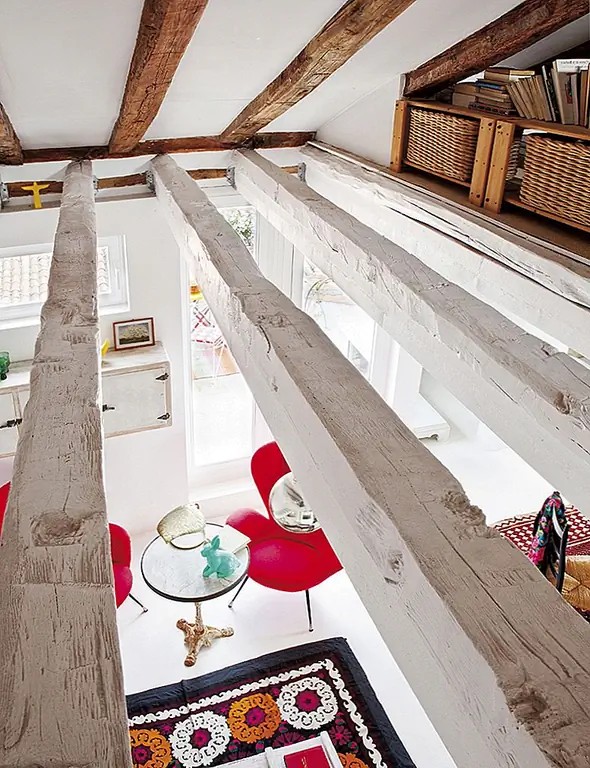 Поднимитесь по лестнице, чтобы добраться до спальни. Наклонная крыша и открытые деревянные балки дают очень привлекательный, расслабляющий и уютный вид. Матрац сидит прямо на полу, поэтому здесь очень необычная атмосфера, акцентированная акцентами на декоре, такими как обрамленные картины, прислонившиеся к стене.