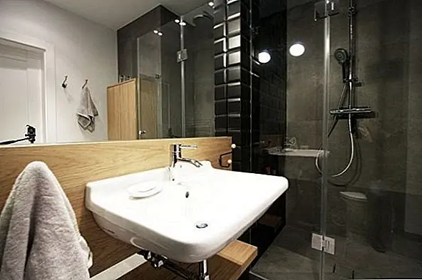 Зеркала - лучший друг небольшого пространства, и эта ванная комната демонстрирует, почему. Пространство светлое, яркое и кажется вдвое большим, чем оно есть на самом деле. Гладкий современный стеклянный душ и окрашенная кирпичная черная плитка добавляют острое изощренность.