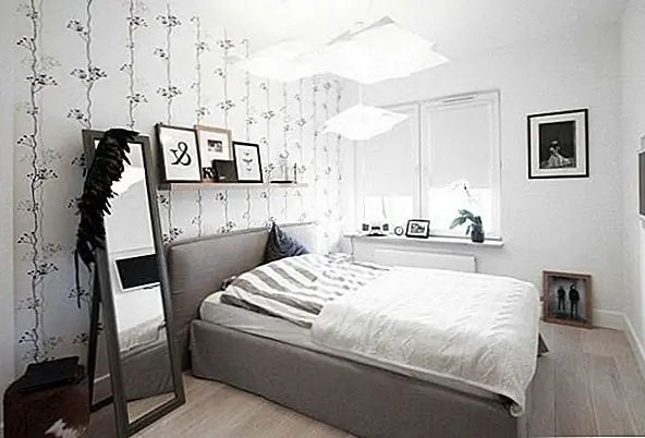 В спальне светлая, нейтральная цветовая палитра продолжается. Обои с вертикальной печатью и наклоняющееся зеркало открывают пространство визуально, а мебель сведена к минимуму. Пространство подогревается деревянными рамами на множестве черно-белых иллюстраций.