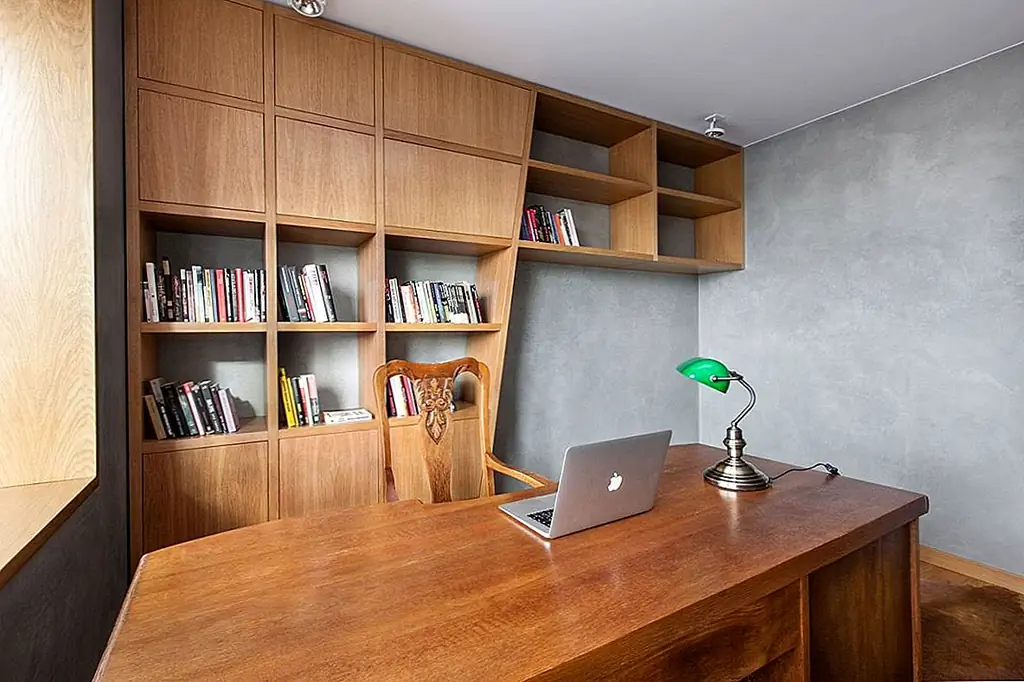 Такая же комбинация серого и дерева была также использована в домашнем офисе, где ассиметричный стеновой блок служит в качестве фокуса и где мягкий животный шкура ковра добавляет текстуру и тепло в пространство. Окна были выставлены для увеличения естественного освещения.