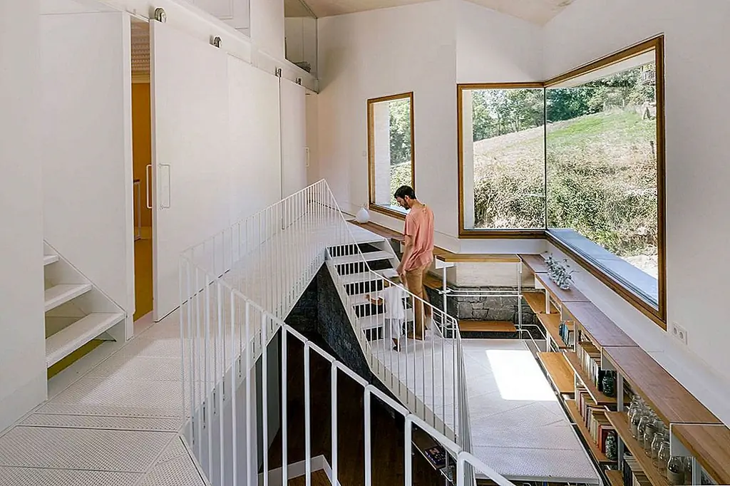 Металлическая лестница с книжными полками вдоль его опорной стенки обеспечивает доступ к остальной части пространства. На первом этаже расположены две спальни. Главная спальня выходит на угловую террасу и предлагает великолепные виды. В промежутке между двумя спальными зонами есть пространство с двойной высотой с видом на долину.