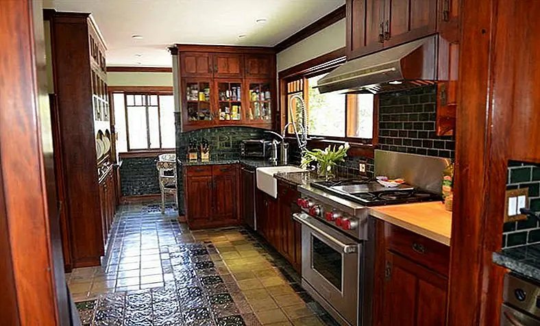 Кухня эмулирует типичный дом мастера, с темными деревянными шкафами и плиточными полами с рисунком с рисунком. Профессиональные приборы из нержавеющей стали обновляют дизайн и функциональность. Фотография компаса.