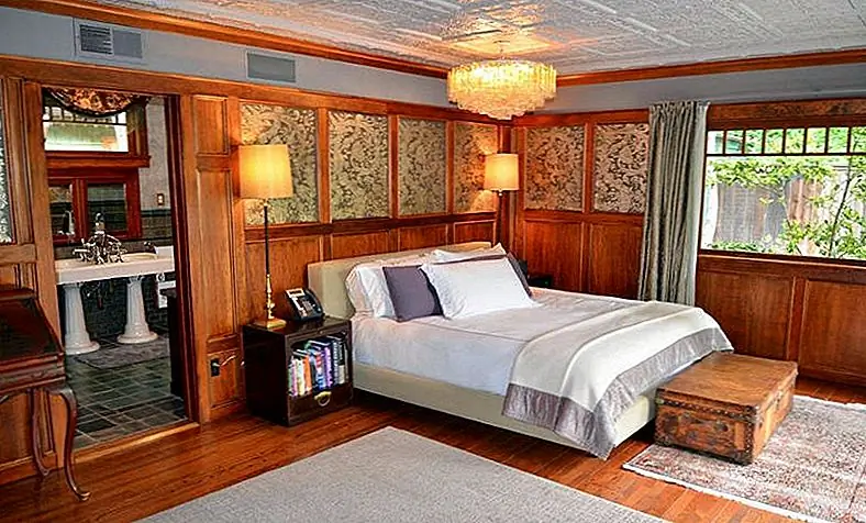 Мастер-люкс использует оригинальную отделку дома мастеров, в том числе теплые деревянные тона, потолок из цинковой плитки и шелковые вышитые тканевые панели за кроватью.