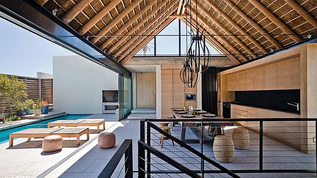 В обеденной зоне установлены большие раздвижные стеклянные двери, которые соединяют его со двором и бассейном. Кухня тоже есть. Открытая древесина и соломенная роза создают уютную и уютную атмосферу. Освещение потолка также помогает определить пространство.