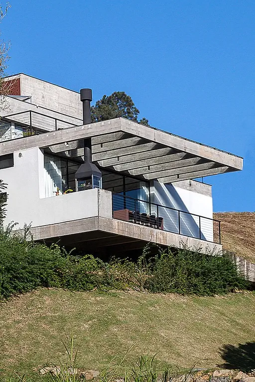 Дом структурирован в два длинных и прямоугольных тома размером 26м x 40м. Более низкий объем содержит социальные пространства и открывается на приостановленную террасу. Он также включает в себя зоны обслуживания и гараж. Верхний уровень поддерживается на одном конце землей, а другой - цилиндрическим столбом, образуя открытую, но защищенную область гаража для двух автомобилей.