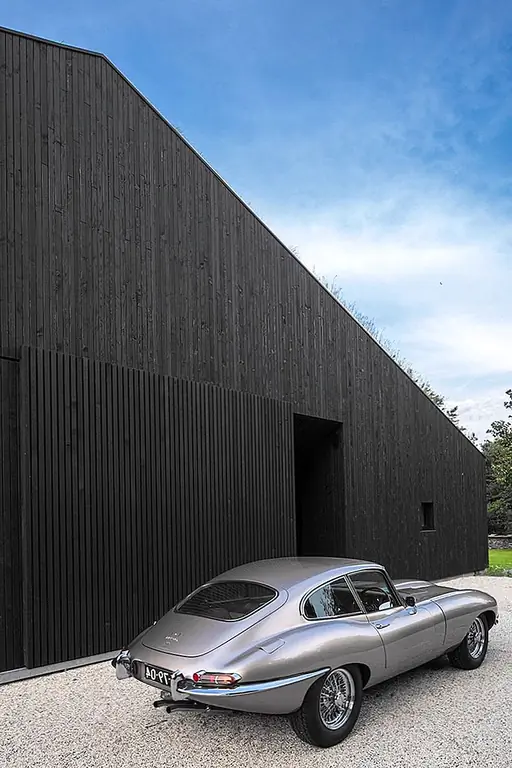 Дом полностью одет в почерневшую древесину, и это происходит в ответ на предпочтение владельца смелым, но скромным и простым дизайном. Интерьер просторный и открытый. Несущие стены способны поддерживать крышу самостоятельно, и это устраняет необходимость в любых конструкционных колоннах, значительно уменьшая беспорядок и разделение пространств. Как упоминалось ранее, дом имеет большие отверстия с каждой стороны. Вход имеет большую застекленную стену и дверь, которая может быть скрыта с помощью раздвижной деревянной панели, когда требуется конфиденциальность или когда дом остается незанятым. Жилая площадь имеет эту очень большую раздвижную дверь, которая составляет около 10 метров и имеет две 20-миллиметровые стеклянные панели весом более 500 кг каждая.