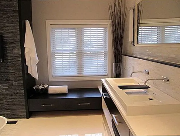 Это прекрасный пример современной ванной комнаты. Он оформлен в минималистском стиле, и здесь есть несколько деталей. Текстура стены акцента и украшение углов - это только детали, которые являются чисто декоративными. В этой ванной комнате есть минималистская двойная раковина, сидящая на функциональном блоке хранения с ящиками и отсеками для хранения. С окном помещена скамья со встроенными ящиками, а подвесное зеркало добавляет глубину в пространство.