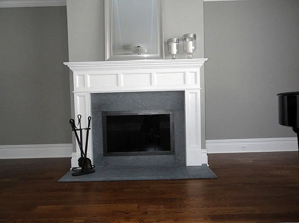 Нейтральная текстура камня хорошо сочетается с белой деревянной каминной полкой. Изображение: KJB Камины