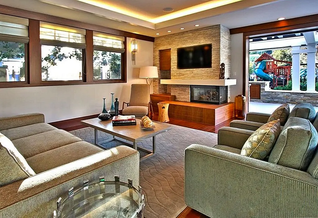 Сочетание теплого дерева и прохладного камня создает захватывающий контраст в этом нецентральном дизайне камина. Изображение: Городская колония