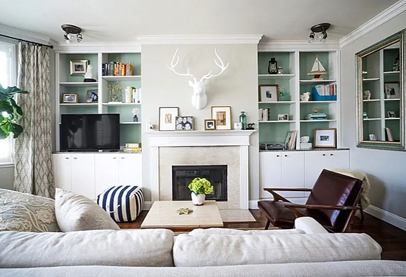 На стеллажах на стенах отображается коллекция стратегически размещенных книг, предметов и искусства. Стены, лежащие за книжными шкафами, окрашены в цвет акцента, чтобы течь с дизайном комнаты. Изображение: Hoister