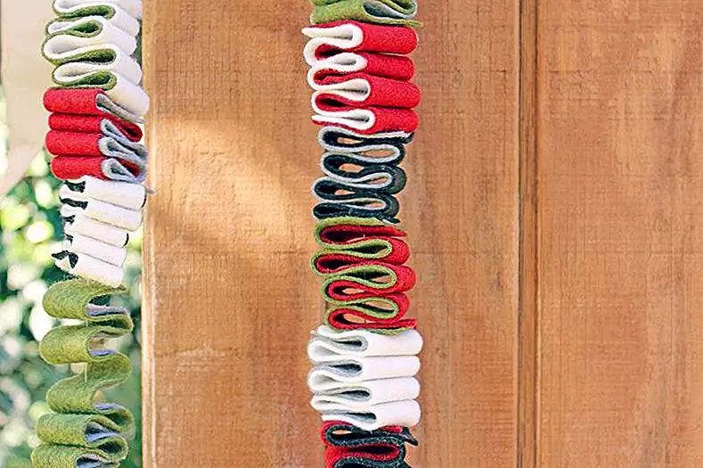 Лента из войлочной гирлянды, представленная на Babbledabbledo, действительно красива и предназначена для того, чтобы вы чувствовали себя в пяти разных цветах, зубной нитью, иглой для вышивания, горячим клеем и ножницами. Обрежьте войлок на 1 "широкие полоски и сложите их. Сделайте полосы длиной около 12 дюймов и разделите их на секции. Возьмите две полосы и выровняйте края. Начните складывать их в 1 "секции. Центрируйте иглу и прошейте через все слои. Затем повторите и, в конце, сшить большие секции вместе.