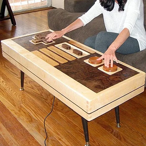 А так как раньше мы обсуждали интерактивные журнальные столики, вот еще один интересный. Это кофейный столик контроллера Nintendo NES, изготовленный из клена, красного дерева и грецкого ореха. Самое интересное в этом состоит в том, что он фактически функциональный и его можно использовать в качестве контроллера для игры в игры. Он оснащен выдвижным шнуром и съемной стеклянной крышкой. Таблица измеряет длину 42 "х 18,25" шириной х 18 дюймов. Доступна для 3700 $.