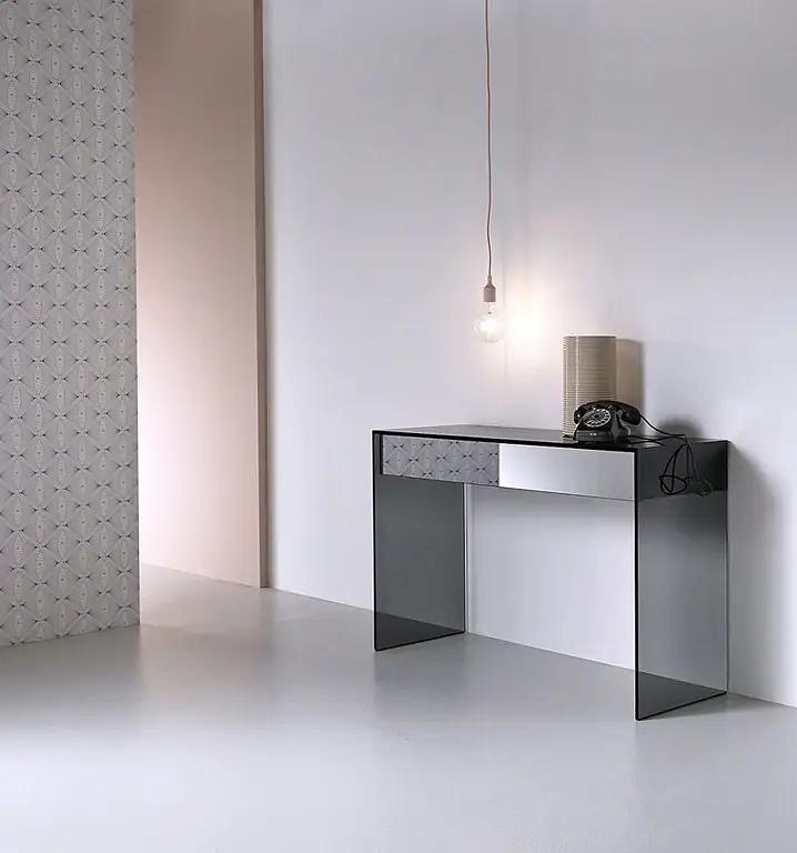 Стол консолей Gotham является частью более крупной коллекции с тем же названием, которая также включает в себя журнальный столик и боковой стол. Консоль выполнена с использованием дымового стекла и имеет простой, но драматический вид благодаря своим чистым, резким линиям и минималистской структуре. Он также включает внутренние деревянные ящики с копченым зеркальным фасадом. Стол был разработан Нико Леонарди и Фабио Маринелли.