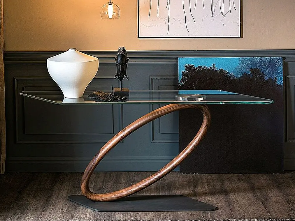 Тур - очень интересная и привлекательная консольная таблица. Он был разработан Джорджо Каттеланом и, похоже, не соответствует законам физики. Он имеет плоское основание из графитовой тисненой лакированной стали и круглую среднюю секцию ореха, расположенную под углом. Верх из прозрачного стекла.