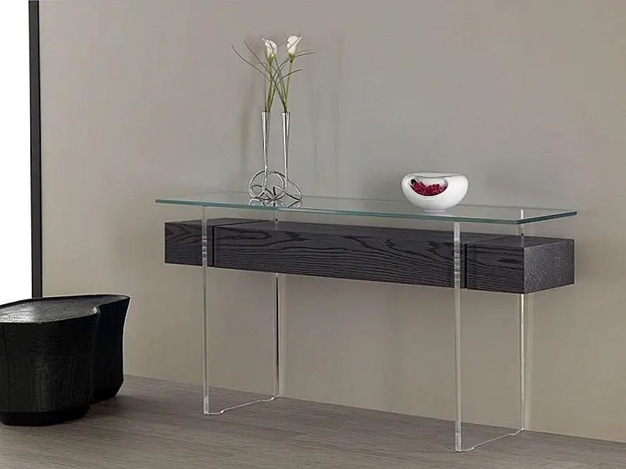 Он был спроектирован Эрваном Пероном и оснащен прочным центральным ящиком из фанеры и дополнительными панелями из дубового шпона. И поддерживающие ножки, и верхние и бесцветные, и сделаны из дополнительного прозрачного закаленного стекла.