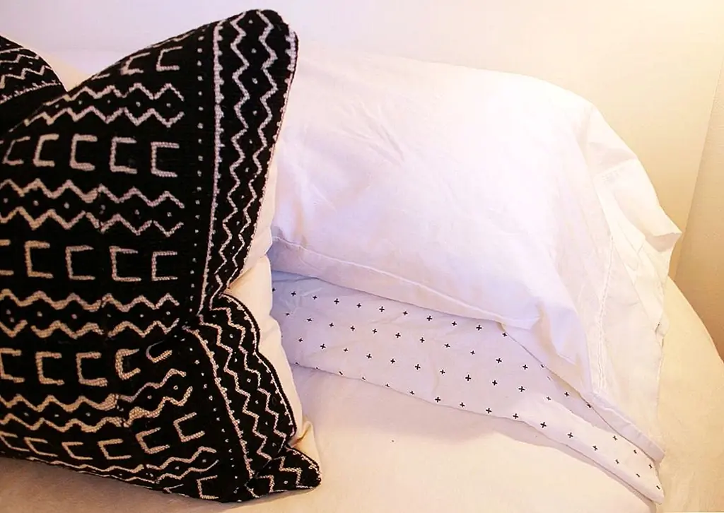 Ключом к минималистской кровати является структура и простота. Две подушки белого цвета (хотя и слегка узорчатые, сладкие) аккуратно и прямо уложены в голове кровати. Броские подушки расположены симметрично перед ними.