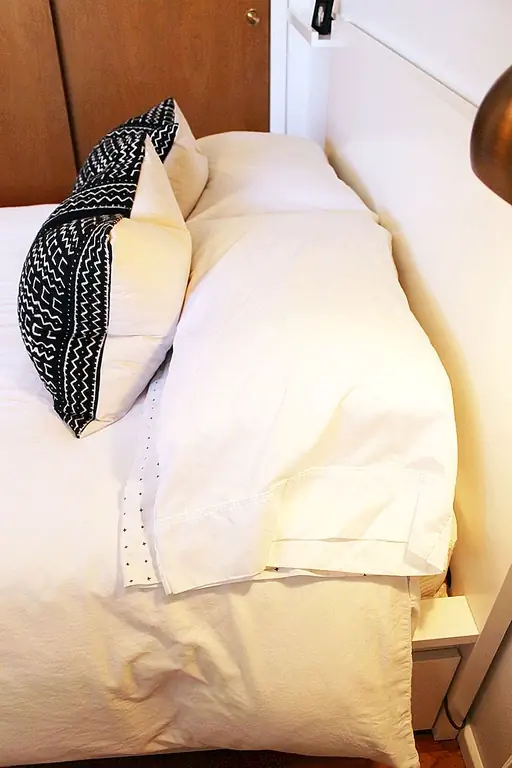 Белое одеяло вытягивается ровно и почти полностью до области изголовья. (Под глазами под открытым небом появляется дополнительный слой под этим пуховым одеялом, хотя фотография его не показывает.) Простая, структурированная, прямая, квадратная. Все эти аллитеративные слова объединяются, чтобы создать красивейшую минималистскую кровать.