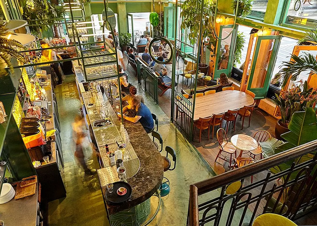 Старые металлические перила были фактически сохранены. Они были окрашены в зеленый цвет, чтобы соответствовать новой теме и включены в недавно разработанный декор. Теперь они отделяют бар от гостиной.