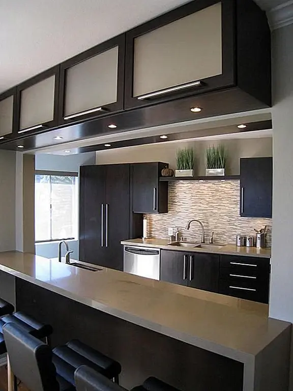 Мало того, что расположение этих шкафов является новаторским и перспективным, но так же сочетаются гладкие черные, никелевое оборудование и матовое стекло. Мы обманываем это современное и стильное кухонное пространство!