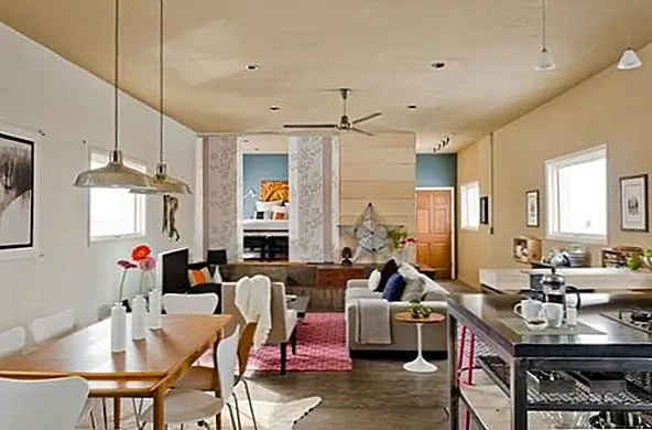 В случае с этим домом все совсем по-другому. Гостиная, кухня и обеденная зона имеют одинаковое пространство. Стиль, выбранный для декора, также современен, но имеет сильные промышленные влияния. На кухне есть металлический остров с открытым хранением, подвесные светильники в промышленном стиле и простой простой и функциональный декор.