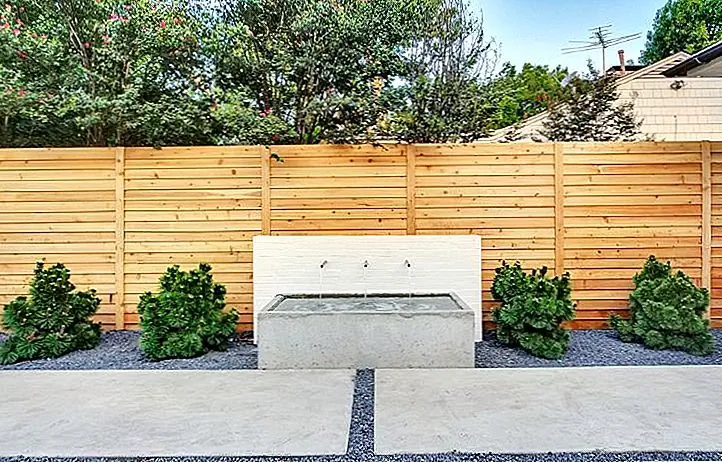 Это прекрасный пример забора, который обеспечивает максимальную конфиденциальность. Он имеет горизонтальные деревянные доски без места между ними. Забор полностью отделяет двор от соседней собственности, не глядя драматично или очень внушительно.