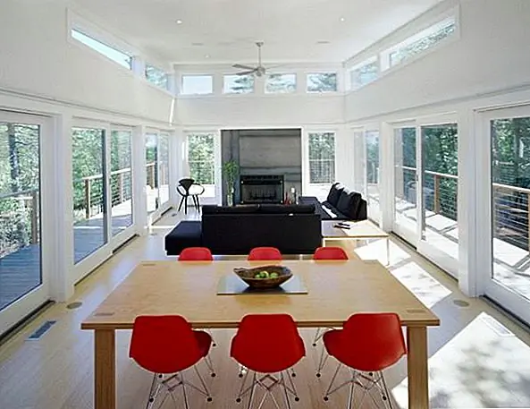 Это современная гостиная, и интересная вещь в этом заключается в том, что в основном есть окна на трех стенах. Это позволяет тоннам естественного света проникать внутрь и позволяет всем полюбоваться прекрасными видами. Декор номера прост и современен. Единственное прикосновение цвета приносят стулья Eames, на этот раз - красным.