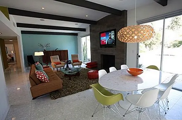 И мы вернулись в столовые. Это на самом деле жилое пространство с открытым этажем. Столовая не четко разделена. Он расположен спереди в окне для более естественного освещения, и он состоит из круглого обеденного стола и восьми боковых стульев Eames, два из которых зеленые. Остальные стулья белые и подходят к столу.